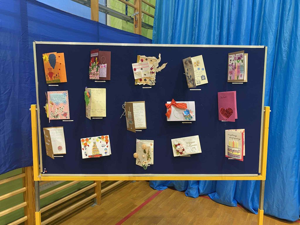Zdjęcie przedstawia 15 kartek urodzinowych przypiętych na tablicy. 