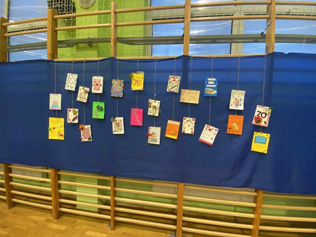 Zdjecie przedstawia 24 kartki urodzinowe przypięte do materiału. 